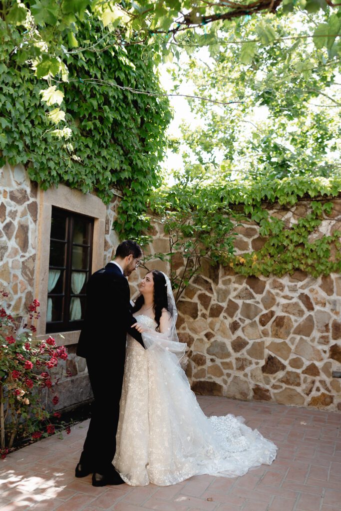 Bride and groom kissing beside ivy covered stone wall at Jacuzzi Winery wedding
